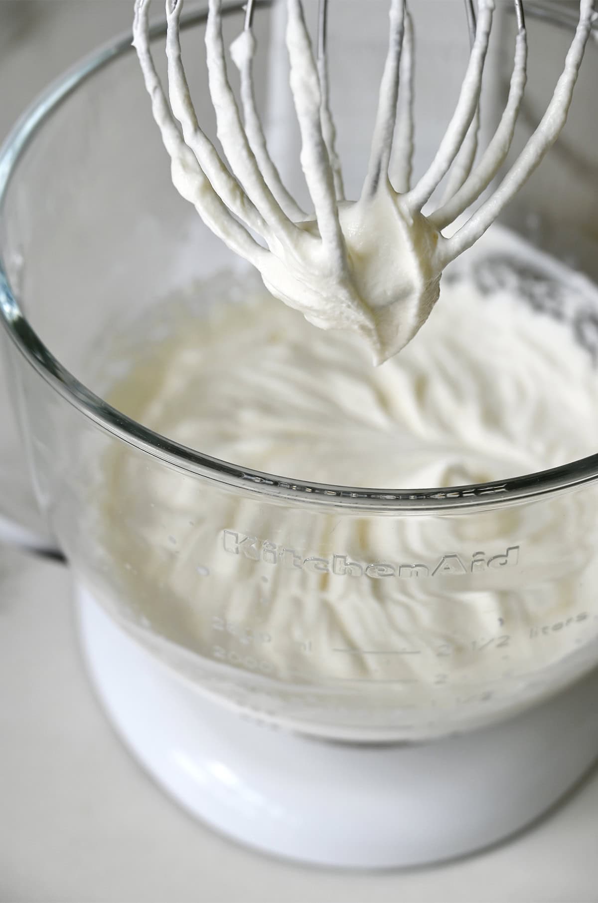 Homemade whipped cream in the bowl of a stand mixer with the whisk attachment.