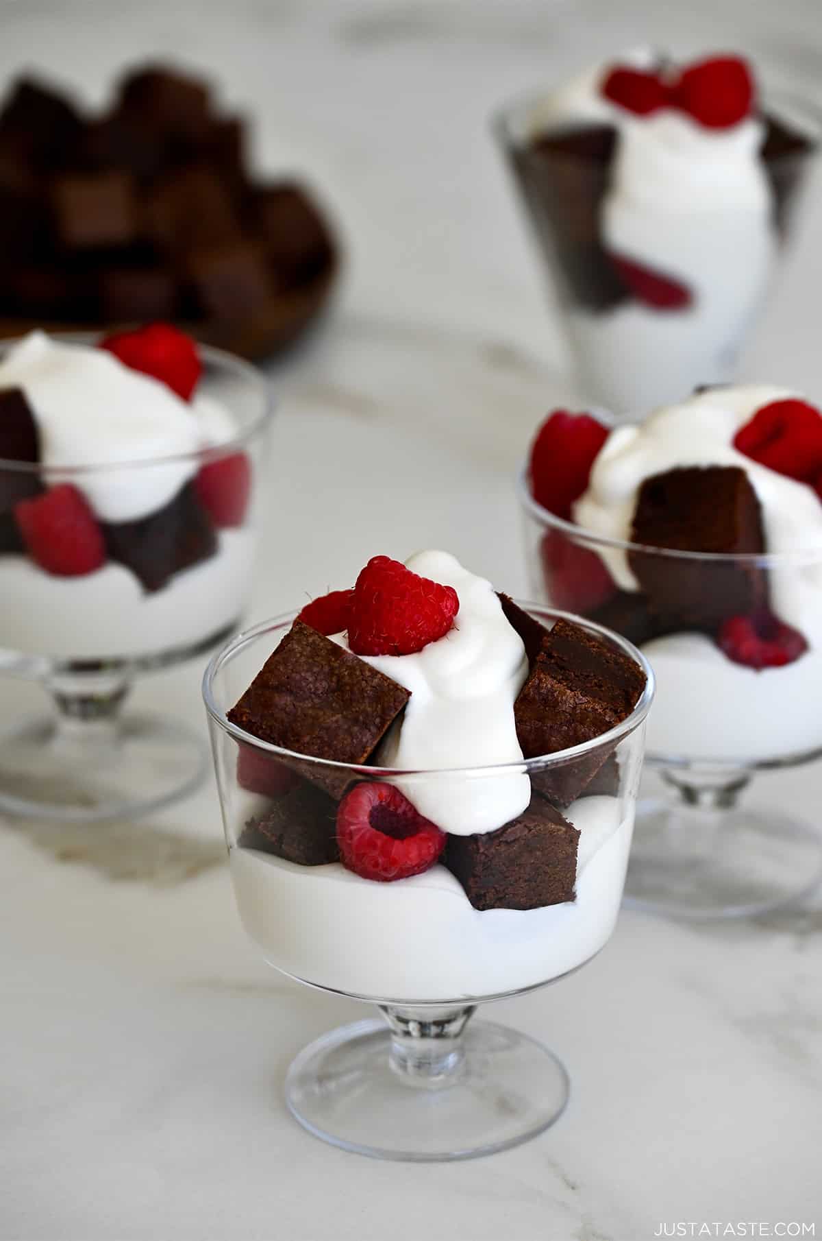 Dessert cups with layers of whipped cream, brownie pieces and fresh raspberries.